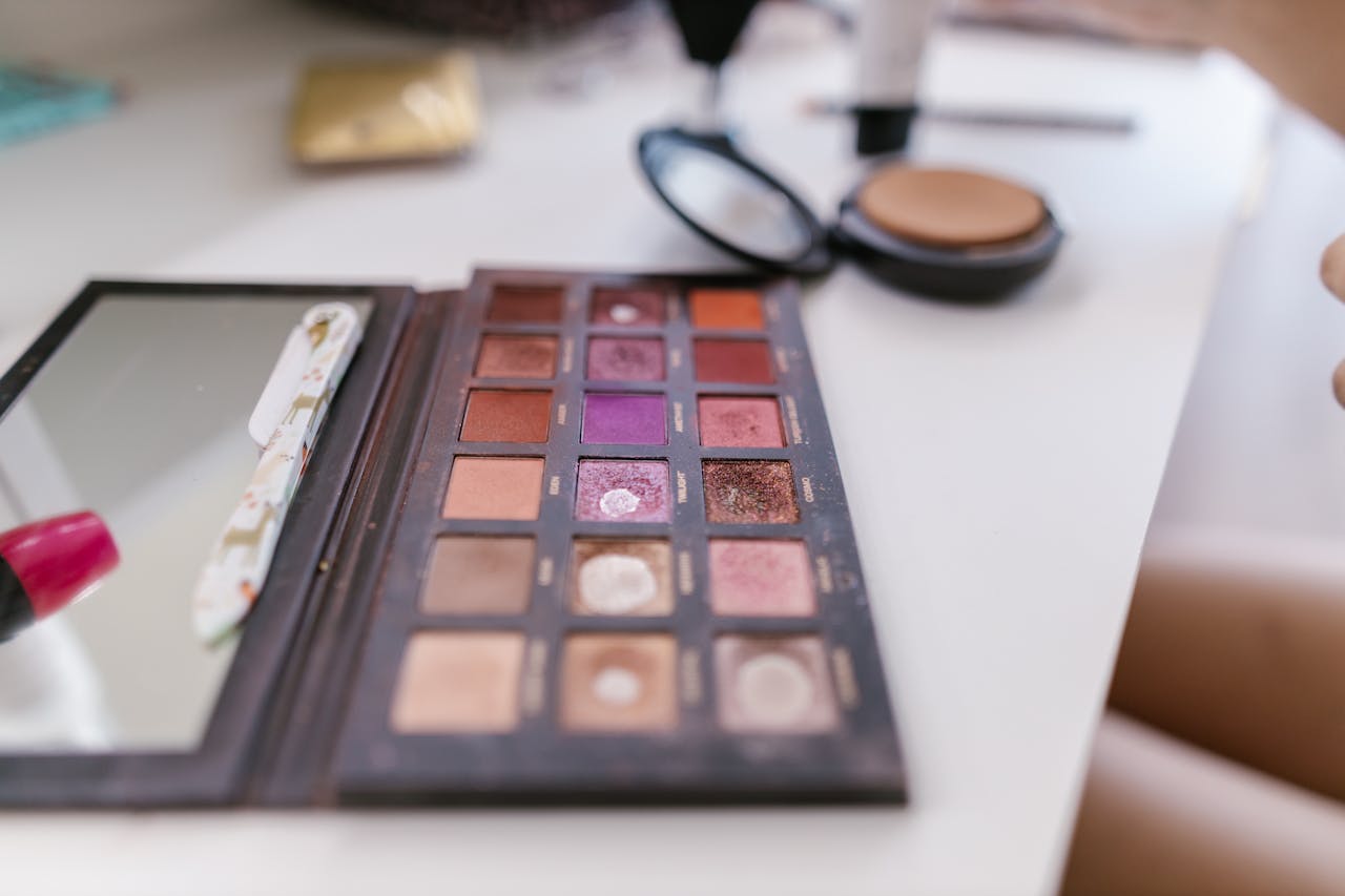 about-01 A detailed close-up of a well-used makeup palette on a white table, showcasing various shades.