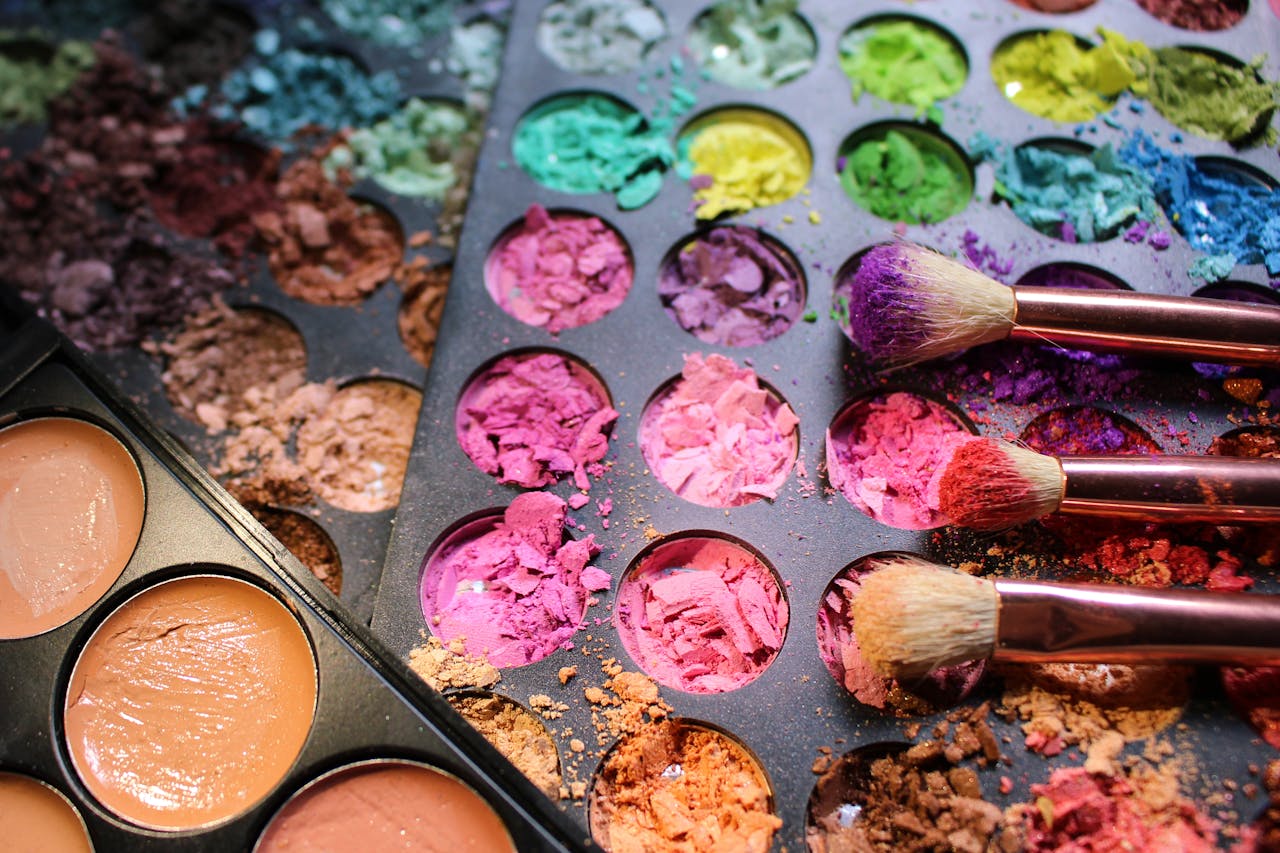 gallery-6 A messy, colorful makeup palette with various pigments and brushes in close-up view, creating an artistic display.