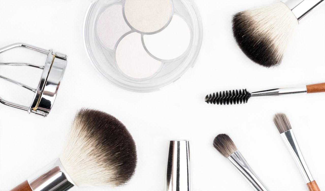 hero-img-02 Flat lay of various makeup brushes and tools on a white background.
