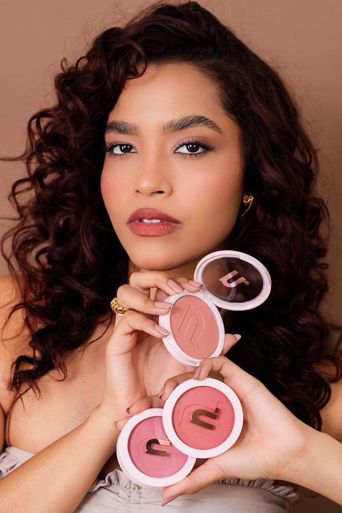 gallery-1 Woman holding three shades of blush compacts in a beauty portrait.