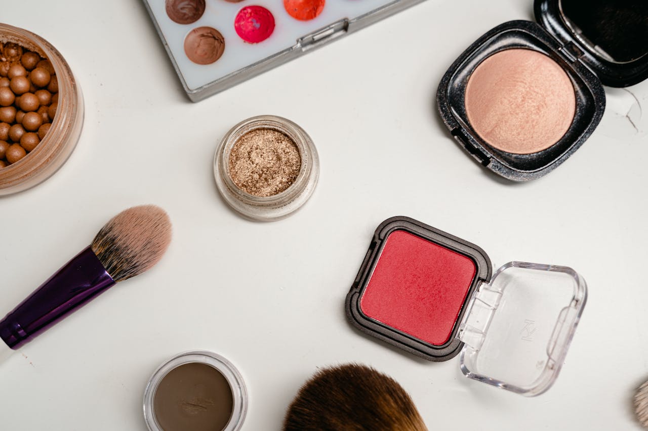 services-01 Flat lay of various makeup products including brushes, powders, and creams on a white surface.